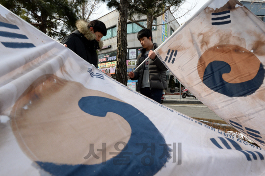 3·1절을 하루 앞둔 29일 서울 은평구 은평구청에서 관계자들이 낡고 찢어진 '진관사 태극기'(등록문화재 제458호)를 게양하고 있다. '진관사 태극기'는 독립운동가 백초월 스님의 절 '진관사'에서 발견된 것으로 구청 측은 지난 26일부터 구내 길가에 진관사 태극기 1300여기를 게양했다고 전했다./권욱기자