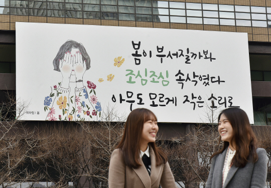 시민들이 2일 서울 광화문 교보생명 사옥에 걸린 광화문글판 앞을 거닐고 있다. 봄을 맞아 새단장한 광화문글판에는 최하림 시인의 시 ‘봄’의 싯구가 담겼다. 모든 것이 귀하고 소중하므로 늘 겸손한 마음으로 서로를 헤아리고 배려하며 살아가자는 메시지를 담았다는 게 교보생명 측 설명이다./사진제공=교보생명