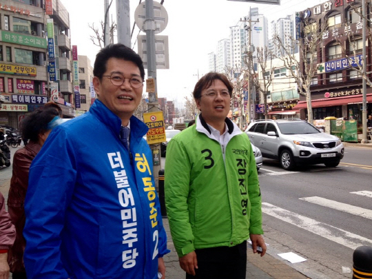 허동준 더불어민주당 후보와 장진영 국민의당 후보가 29일 “야권분열 어부지리, 새누리는 웃고 경제는 웁니다”라고 적힌 더불어민주당 현수막을 보며 이야기를 나누고 있다.