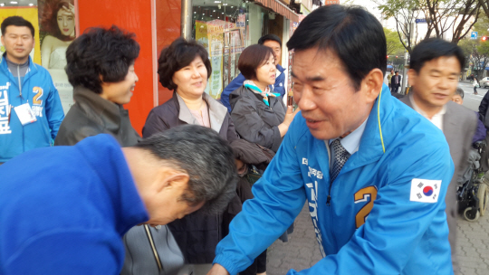 경기 수원무에 출마한 김진표 더불어민주당 후보가 11일 권선2동에서 한 유권자와 악수를 하고 있다.