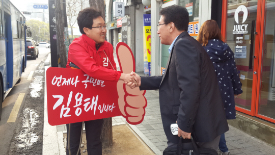 서울 양천을에 출마한 김용태(왼쪽) 새누리당 후보가 12일 목동역 출구에서 목발을 짚은 채 유권자와 악수를 하고 있다. /지민구기자