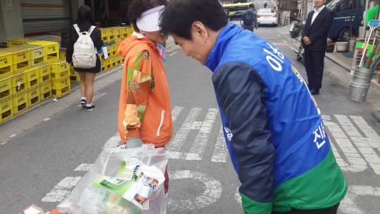 서울 양천을에 출마한 이용선(오른쪽) 더불어민주당 후보가 12일 신정역 인근 골목에서 유권자에게 아침 인사를 하고 있다. /지민구기자