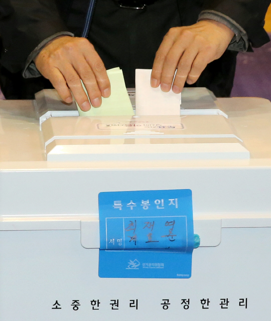 20대 총선이 열린 13일 서울 종로구 청운효자동 제1투표소에서 한 유권자가 투표함에 투표용지를 넣고 있다. /연합뉴스