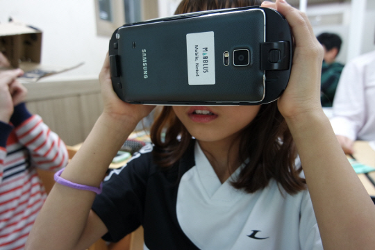 서울 성동구 지역아동센터의 한 초등학생이 SK행복나눔재단이 만든 사회적기업 ‘행복한학교’가 진행하는 가상현실(VR)기기 영어회화 수업에 참여하고 있다. VR 프로그램은 벤처기업 마블러스가 만들었다./사진제공=SK행복나눔재단