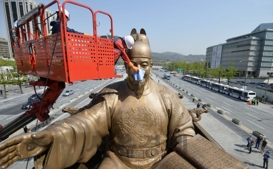 18일 오전 서울 세종대로 세종대왕상에서 작업자들이 크레인에 올라 동상 물청소를 마친뒤  뒤 헝겊으로 물기를 닦아내고 있다./송은석기자