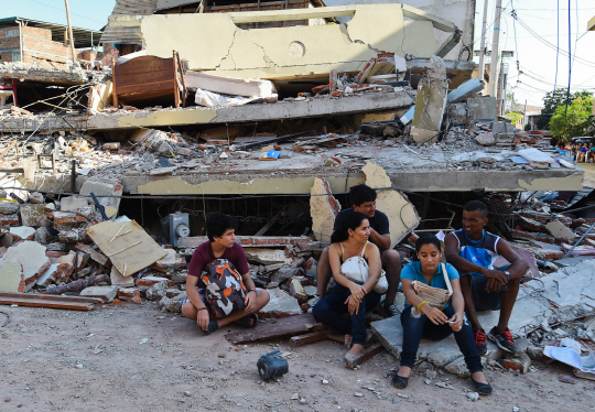17일(현지시간) 에콰도르 서부 해안도시 만타에서 이재민들이 지진으로 무너져내린 건물 앞에서 망연자실한 표정으로 주저앉아 있다. 에콰도르 정부는 군인 1만명과 경찰 4,600명을 투입해 긴급 복구작업을 벌이고 있지만 여진과 장비 부족으로 어려움을 겪는 것으로 전해졌다.  /만타=AFP연합뉴스