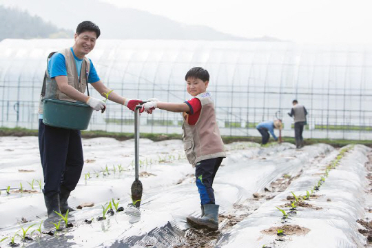 22일 강원도 홍천군 남면 명동리 마을에서 진행된 대한항공 임직원과 의료봉사단이 농촌일손돕기에서 대한항공 직원과 마을 어린이가 함께 일하며 기념 촬영을 하고 있다./사진제공=대한항공