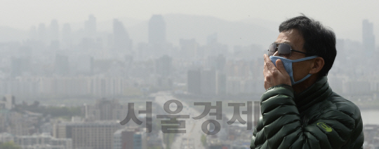 전국 대부분 지역에 미세먼지 주의보가 발령된 24일 서울 남산 인근에서 마스크를 쓴 시민 너머로 서울 하늘이 흐린 모습을 보이고 있다./송은석기자songthomas@sedaily.com