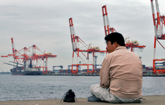 일본 요코하마 항구에서 한 남자가 허탈한 표정으로 화물선 선적 장면을 바라보고 있다. 신흥국 경기 둔화와 엔화 강세가 겹치면서 일본 기업들은 해외 수출에 어려움을 겪고 있다. /자료=블룸버그