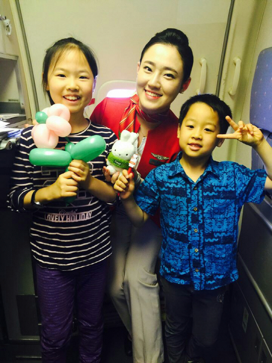 티웨이항공 승무원이 마스코트인 부토와 풍선 아트를 어린이 고객에게 선물하고 기념 촬영을 하고 있다./사진제공=티웨이항공