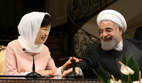 로하니 이란 대통령이 2일(현지시간) 사드아바드 좀후리궁에서 열린 한·이란 정상 공동기자회견에서 박근혜 대통령의 마이크가 나오지 않자 자신의 마이크를 건네며 환하게 웃고 있다. /테헤란=연합뉴스