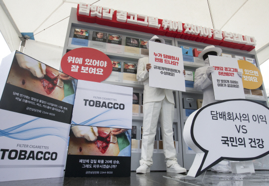 한국금연운동협의회 관계자들이 10일 서울 광화문광장에서 담뱃갑 경고그림 상단 배치를 촉구하는 퍼포먼스를 하고 있다. 이들은 경고그림을 담뱃갑 상단에 배치해야 흡연자는 물론 주변인들에게 높은 노출 효과를 준다고 주장했다.  /연합뉴스