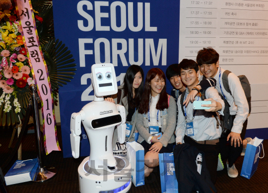 11일 서울 중구 신라호텔에서 열린 ‘서울포럼 2016’에 참석한 대학생들이 행사장에 전시된 실버케어 로봇 ‘로보케어’와 기념사진을 찍고 있다.  /권욱기자