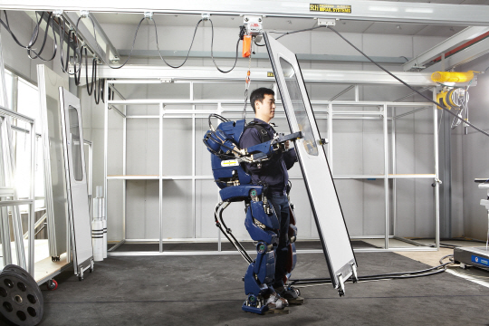 현대로템 의왕연구소에서 한 작업자가 산업용 로봇 RMX-HI를 타고 무거운 금속판을 들어올리고 있다. /사진제공=현대로템
