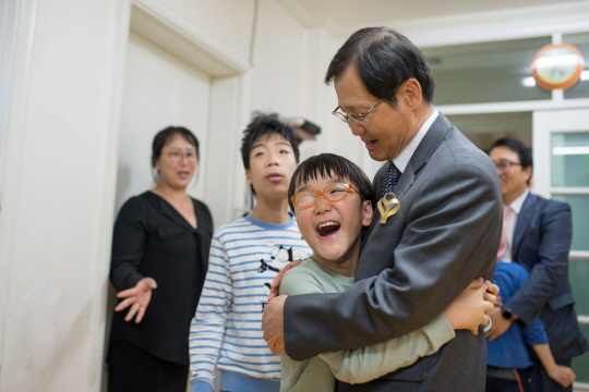 박찬구(앞줄 오른쪽) 금호석유화학그룹 회장이 16일 서울 암사재활원을 찾아 중증 장애인들에게 맞춤형 휠체어를 선물한 뒤 장애아동을 안고 활짝 웃고 있다. 금호석유화학은 지난 2008년부터 9년째 수도권 장애인 거주시설에 맞춤형 휠체어 등의 보장구를 지원해왔다. /사진제공=금호석유화학