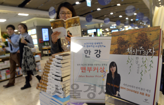 소설가 한강이 맨부커상을 수상한 다음날인 17일 서울 광화문 교보문고에서 한 독자가 서가에 전시돼 있는 ‘채식주의자’를 읽고 있다.   /이호재기자