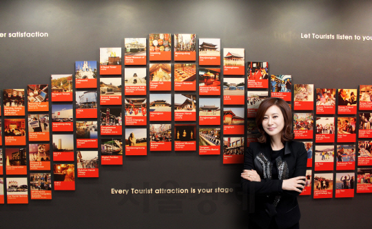 정명진 코스모진 대표가 서울 을지로 본사 내 벽에 전시된 국내 여행 명소 사진들 앞에서 포즈를 취하고 있다./사진제공=코스모진