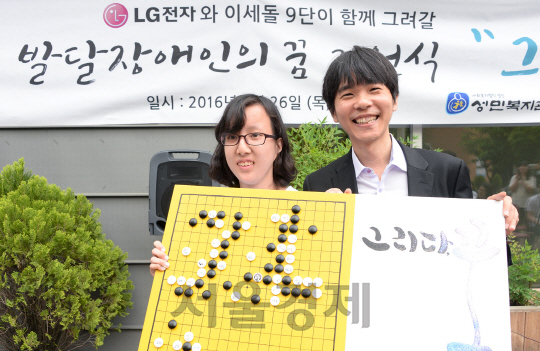 이세돌(오른쪽) 9단이 26일 서울 노원구 성민복지관에서 성민직업대학 학생이 그린 기보 그림을 받고 환하게 웃고 있다. /사진제공=LG전자