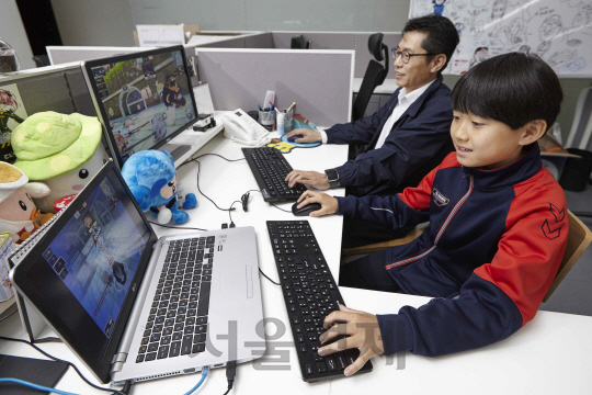 윤희용(왼쪽) 씨와 아들 윤성현 군이 함께 ‘버블파이터’ 게임을 즐기고 있는 모습./ 사진제공=넥슨