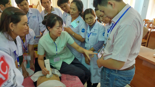 힐세리온 관계자(가운데)가 휴대용 무선 초음파 진단기 ‘소논’을 사용해 환자의 복부 상태를 점검하자 베트남 광찌성 보건당국 직원들이 유심히 지켜보고 있다 . / 사진제공=힐세리온