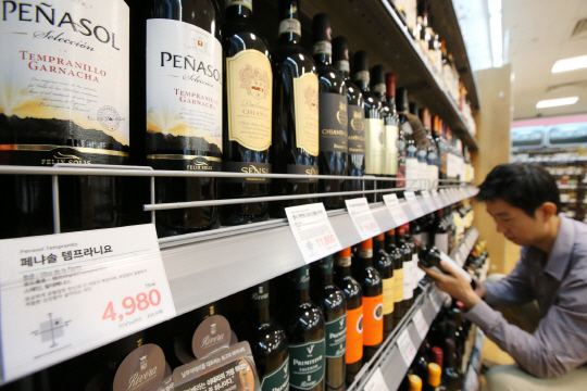 유통마진을 줄인 저가 와인이 인기다. 이마트에 따르면 올해 1월부터 지난달 30일까지 가장 많이 판매된 와인(수량 기준) 1∼5위에 모두 1만원 미만 제품이 올랐다. 롯데마트에서도 전체 와인 매출에서 1만원 이하 제품이 차지하는 비중은 지난해 46.8%에서 올해 51.3%로 절반을 넘어섰다. 13일 서울시내 한 대형마트에서 고객이 와인을 고르고 있다. /연합뉴스