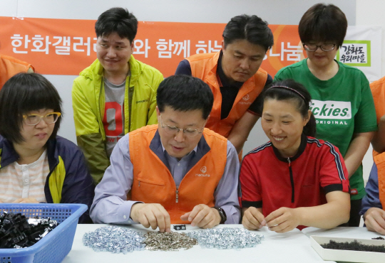 한화갤러리아 임직원 봉사단은 16일 발달장애인 직업재활시설인 강화도 우리마을을 방문해 봉사활동을 했다. 봉사단은 우리마을에 쌀 450㎏을 전달하고 우리마을의 수익사업인 부품 조립 작업을 도왔다. 황용득(앞줄 왼쪽 두번째) 한화갤러리아 대표가 시설 장애인들과 부품을 조립하고 있다. /사진제공=한화갤러리아