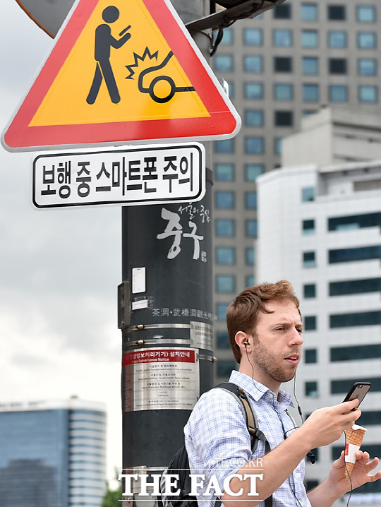 한 외국인 남성이 16일 오전 서울광장 앞 횡단보도에서 스마트폰을 하고 있다.