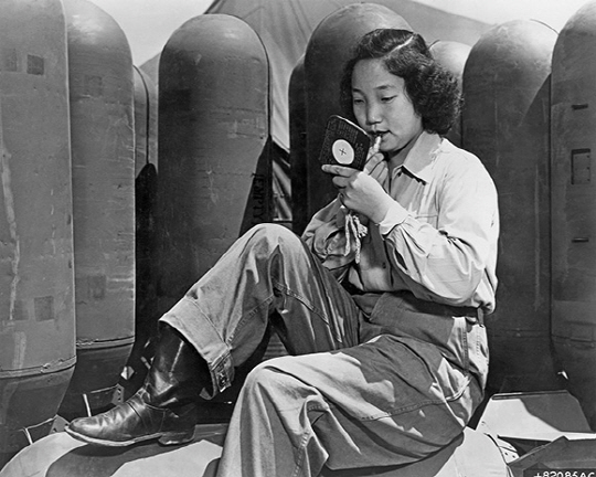 한 한국 여성이 6·25 전쟁 도중 포탄 위에 앉아 화장을 하고 있다. 이 여성은 6.25 전쟁 당시 남측 심리전단 소속으로 미 공군기에 올라 전선을 저공비행하며 확성기를 통해 중공군 상대로 사기를 떨어뜨리는 말을 하는 일을 맡았다(1952년 11월 10일, AP통신). / 사진제공=서울역사박물관