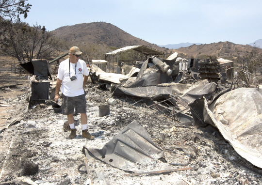 27일(현지시간) 미국 캘리포니아주에서 거주하는 한 시민이 산불에 모두 타버린 자신의 집을 살펴보고 있다./사우스레이크=AP연합뉴스