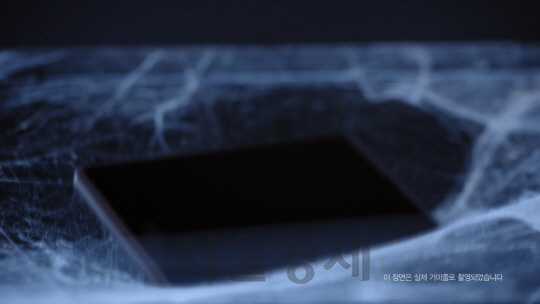 6일 LG유플러스가 공개한 이색 광고 영상에서 스마트폰 ‘X스킨(Skin)’이 거미줄 위에 안착하며 가벼운 무게를 증명해 보이고 있다./사진제공=LG유플러스
