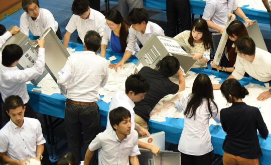 10일 저녁 일본 도쿄의 한 선거 개표소에서 개표 사무원들이 이날 치러진 참의원 선거 투표함에서 투표용지를 꺼내고 있다. 이날 선거에서 아베 신조 총리가 이끄는 집권여당은 압승을 거둔 것이 확실시되고 있다.  /도쿄=AFP연합뉴스