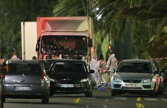 15일(현지시간) 사고 수습에 나선 경찰 관계자들이 니스 테러에 사용된 25톤 대형트럭 주변을 살피고 있다. /니스=AP연합뉴스