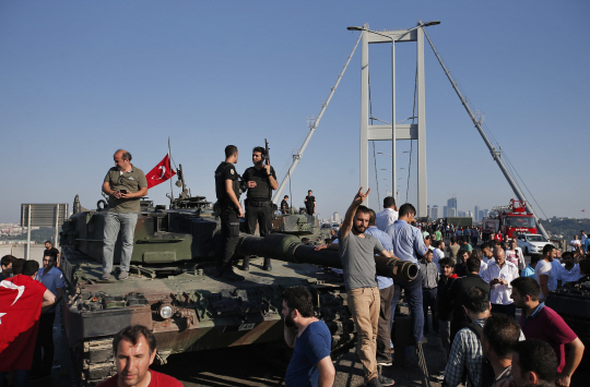 People gather for celebration around Turkish police officers, loyal to the government, standing atop tanks abandoned by Turkish army officers, against a backdrop of Istanbul‘s iconic Bosporus Bridge, Saturday, July 16, 2016. Turkish President Recep Tayyip Erdogan declared he was in control of the country early Saturday as government forces fought to squash a coup attempt during a night of explosions, air battles and gunfire that left dozens dead. (AP Photo/Emrah Gurel)      <저작권자(c) 연합