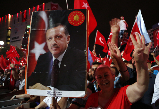 레제프 타이이프 에르도안 터키 대통령의 초상화와 터키 국기를 손에 든 친정부 시위대가 20일(현지시간) 수도 앙카라의 크즐라이 광장에서 국가비상사태 선포를 환영하는 집회를 열고 있다.   /앙카라=AP연합뉴스