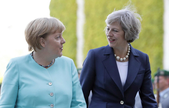 독일을 방문한 테리사 메이 영국 총리가 20일(현지시간) 베를린 독일총리 공관에서 열린 환영행사에 참석해 앙겔라 메르켈 독일 총리와 담소하며 걷고 있다. 두 여성 정상의 만남은 메이 총리 취임 이후 처음이다. 두 정상은 이날 화기애애한 분위기 속에서 정상회담을 열었지만 브렉시트(영국의 유럽연합 탈퇴, Brexit) 협상 시기에 대해서는 명확한 입장차이를 보였다.  /베를린=AP연합뉴스