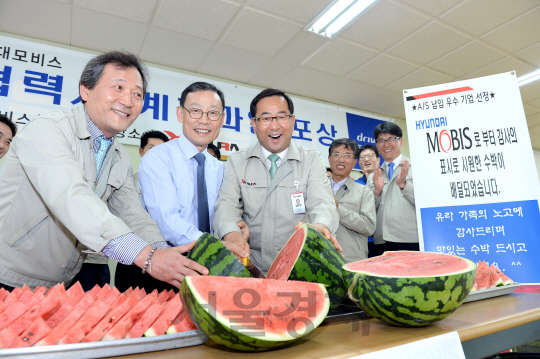 노태호(앞줄 가운데) 현대모비스 통합구매담당 상무가 우수 협력사인 유라하네스를 찾아 직원들에게 나눠 줄 수박을 자르고 있다. /사진제공=현대모비스