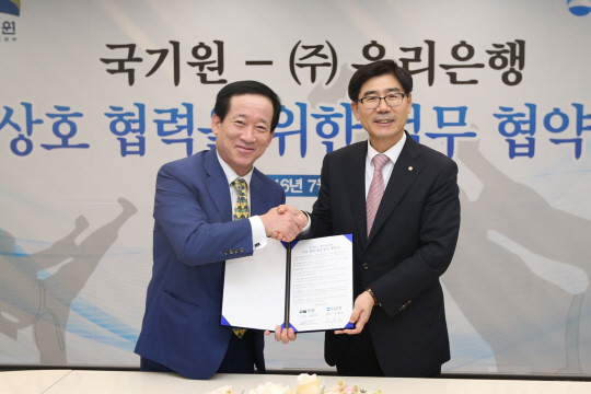 지난 27일 서울 중구 소공로 우리은행 본점에서 이광구(오른쪽) 우리은행장이 오현득 국기원장과 ‘우리은행-국기원, 상호협력을 위한 포괄적 업무협약’을 체결하고 있다./사진제공=우리은행