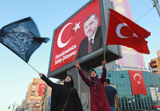 2일(현지시간) 터키 수도 앙카라에서 에르도안 대통령을 지지하는 여성들이 국기와 아랍어가 적힌 검을 깃발을 들고 손을 흔들고 있다. 이날 에르도안 대통령은 지난달 발생한 군부의 쿠데타 시도 배후는 외국이라고 거듭 말했다. /앙카라=AFP연합뉴스