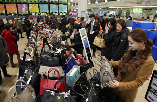 지난해 한 대형마트가 개최한 명품 대전에서 소비자들이 판매대에 가득 쌓인 명품백을 살펴보고 있다./서울경제DB