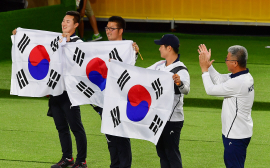 6일 오후(현지시간)  브라질 리우데자네이루 마라카낭 삼보드로무 양궁장에서 열린 2016 리우올림픽 양궁 남자 단체전에서 금메달을 차지한 한국 선수들이 태극기를 들어보이고 있다. 왼쪽부터 구본찬, 김우진, 이승윤, 박채순 감독. /리우데자네이루=올림픽사진공동취재단