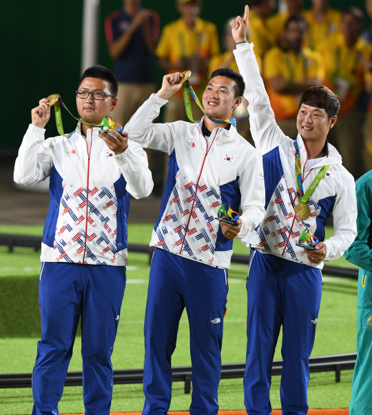 남자양궁대표팀의 김우진(왼쪽부터)·구본찬·이승윤이 7일(한국시간) 브라질 리우데자네이루 마라카낭의 삼보드로무경기장에서 열린 2016리우올림픽 양궁 남자 단체전 결승에서 미국을 꺾은 뒤 시상식에서 금메달을 목에 건 채 환하게 웃고 있다.     /리우데자네이루=올림픽사진공동취재단