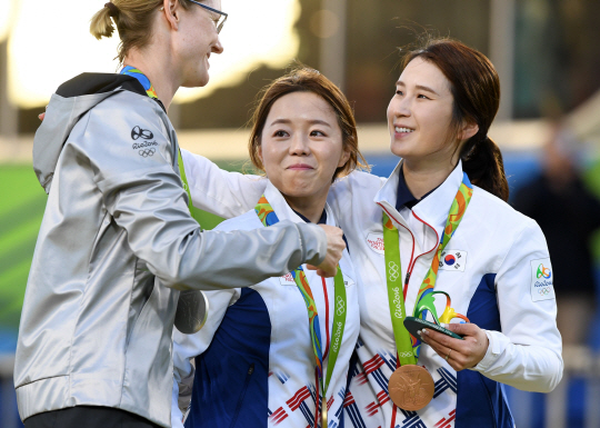 여자양궁 대표팀 장혜진이 11일 오후(현지시간) 브라질 리우데자네이루 마라카낭 삼보드로무 양궁장에서 열린 2016 리우 올림픽 양궁 여자 개인전 결승에서 승리하며 금메달을 획득했다. 시상대에 오른 장혜진과 기보배가 은메달을 따낸 독일의 리사 운루와 서로를 축하하고 있다./리우데자네이루=올림픽사진공동취재단