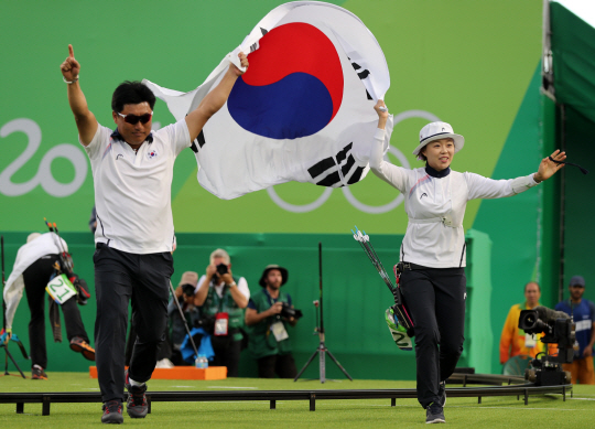 11일 오후(현지시간) 브라질 리우데자네이루 마라카낭 삼보드로무 양궁장에서 열린 2016 리우올림픽 양궁 여자 개인전에서 우승한 장혜진이 양창훈 감독과 태극기를 들고 세레머니를 하고 있다. /리우데자네이루=올림픽사진공동취재단