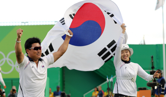 11일 오후(현지시간) 브라질 리우데자네이루 마라카낭 삼보드로무 양궁장에서 열린 2016 리우올림픽 양궁 여자 개인전에서 우승한 장혜진이 양창훈 감독과 태극기를 들고 세레머니를 하고 있다. /리우데자네이루=올림픽사진공동취재단