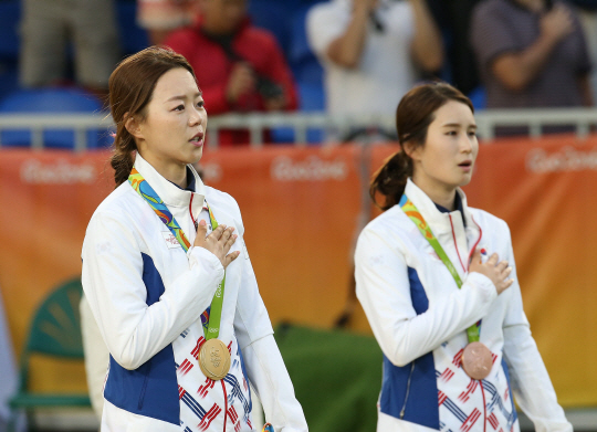 11일 오후(현지시간) 리우데자네이루 마라카낭 삼보드로무에서 열린 여자 양궁 개인전에서 금메달을 딴 장혜진(왼쪽)이 애국가를 부르던 중 눈물을 흘리고 있다. /리우데자네이루=올림픽사진공동취재단