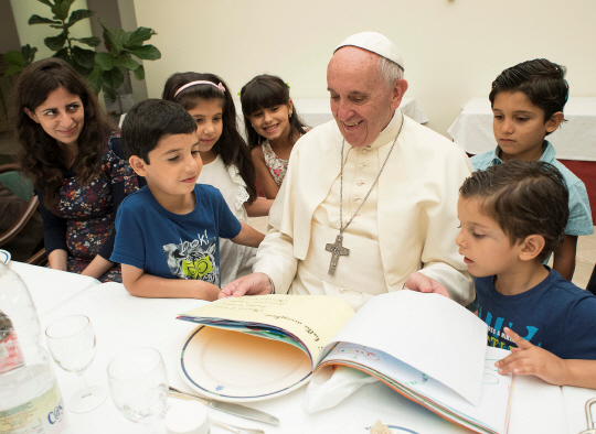 프란치스코 교황이 11일(현지시간) 자신의 숙소인 바티칸 카사 산타마르타에 시리아 난민 어린이들을 초청해 책을 읽어주고 있다. 교황청은 이날 참석한 난민 21명이 교황과 식사를 함께 하며 이탈리아에서 새로운 삶을 시작한 자신들의 사연을 이야기했다고 전했다.   /바티칸시티=AFP연합뉴스