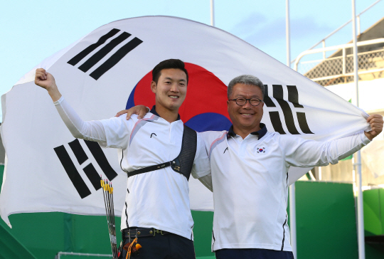 12일 오후(현지시간) 리우데자네이루 마라카낭 삼보드로무에서 열린 남자 양궁 개인전에서 구본찬이 금메달을 목에 걸었다. 결승전에서 구본찬이 금메달을 확정한 뒤 박채순(오른쪽) 감독과 함께 태극기를 들고 환호하고 있다./리우데자네이루=올림픽사진공동취재단