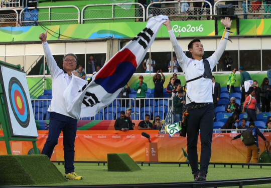 12일 오후(현지시간) 리우데자네이루 마라카낭 삼보드로무에서 열린 남자 양궁 개인전에서 구본찬이 금메달을 목에 걸었다. 결승전에서 구본찬이 박채순(왼쪽) 감독과 금메달을 확정한 뒤 태극기를 들고 환호하고 있다./리우데자네이루=올림픽사진공동취재단