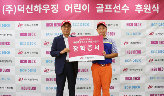 김명환(왼쪽) 덕신하우징 회장이 17일 서울 본사에서 열린 ‘어린이 골프선수 후원식’에서 유지존 군에게 장학증서를 전달하고 있다.  /사진제공=덕신하우징