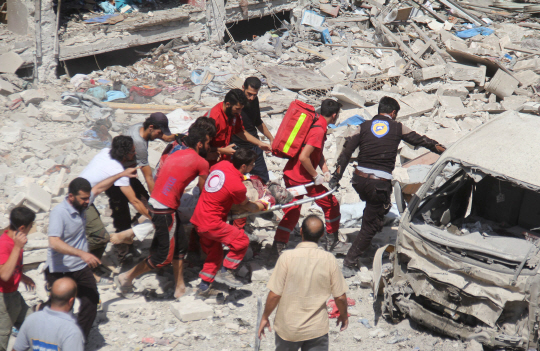 17일(현지시간) 시리아 알레포 지역에서 구급대원들이 공습으로 무너진 건물 잔해에서 사람을 꺼내고 있다. 지난 2011년 4월 시작한 시리아 내전으로 지금까지 29만명이 넘는 이들이 사망했다. /알레포=AFP연합뉴스